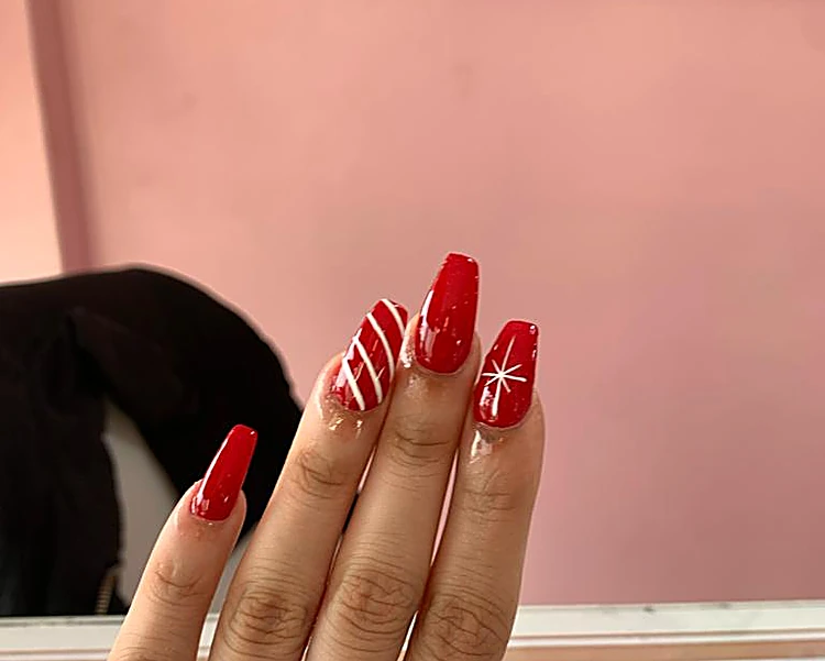 Uñas largas rojas en forma de bailarina con un diseño de bastón navideño rojo y blanco