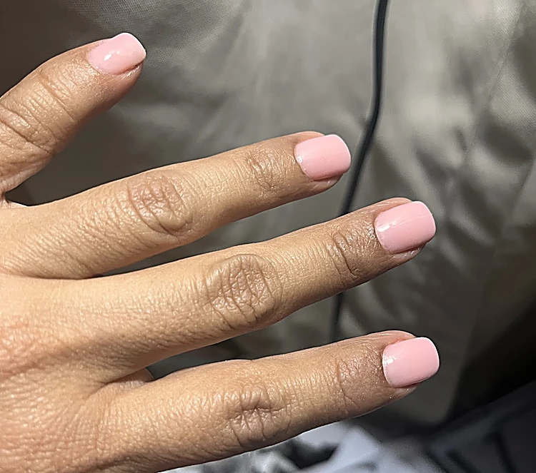 Uñas cortas cuadradas en rosa nude sobre un cojín gris
